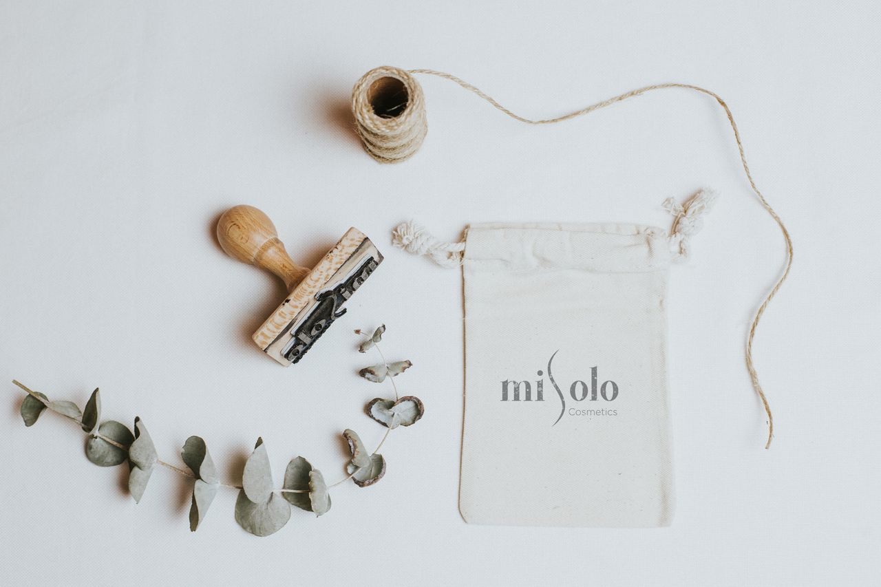 home-hero-bg Emballage de cosmétiques bio avec des éléments naturels et un tampon sur fond blanc.